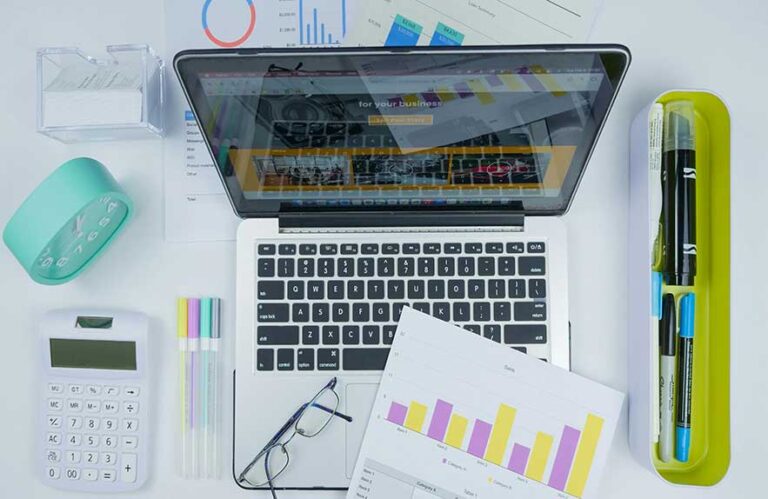 Laptop surrounded by charts, planner tools, and a calculator — representing productivity apps for work and life.